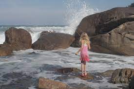 A girl stands on the seashore.