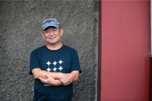 A Korean older man standing with arms folded